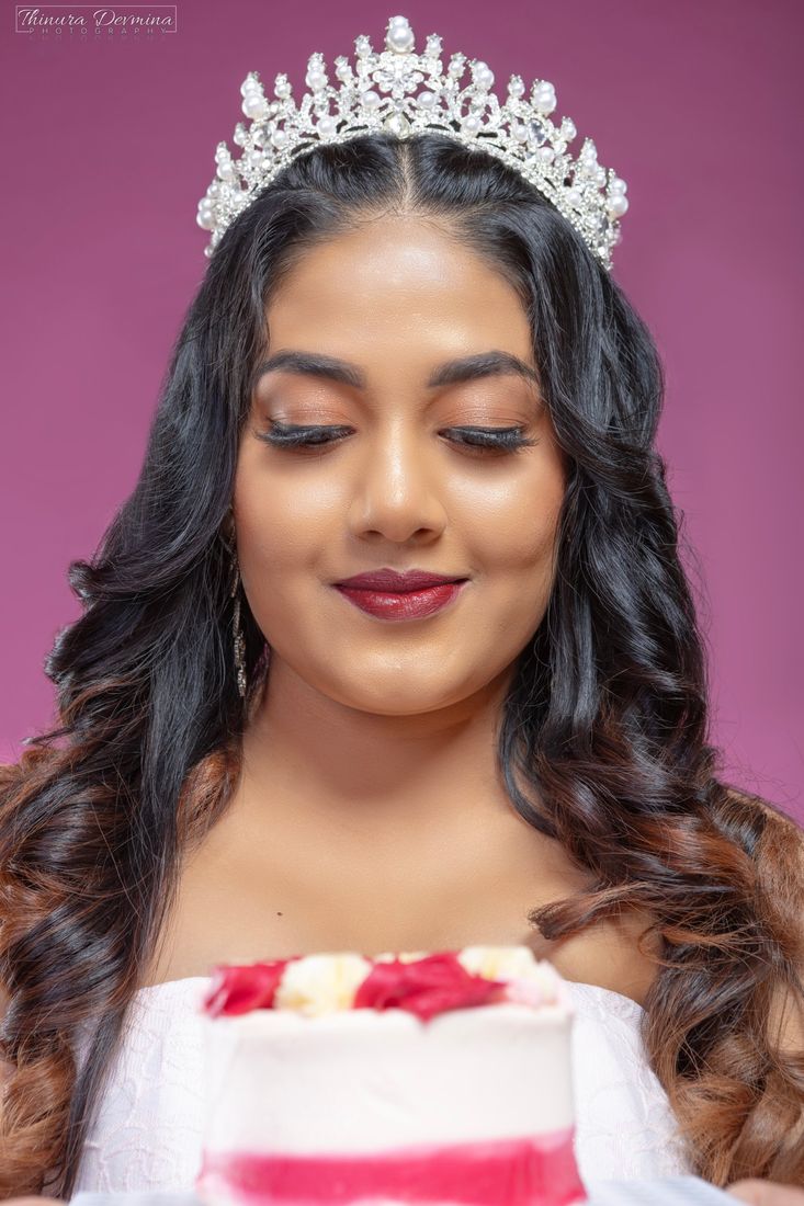 Close-up of a smiling birthday girl in a crown looking down at her cake