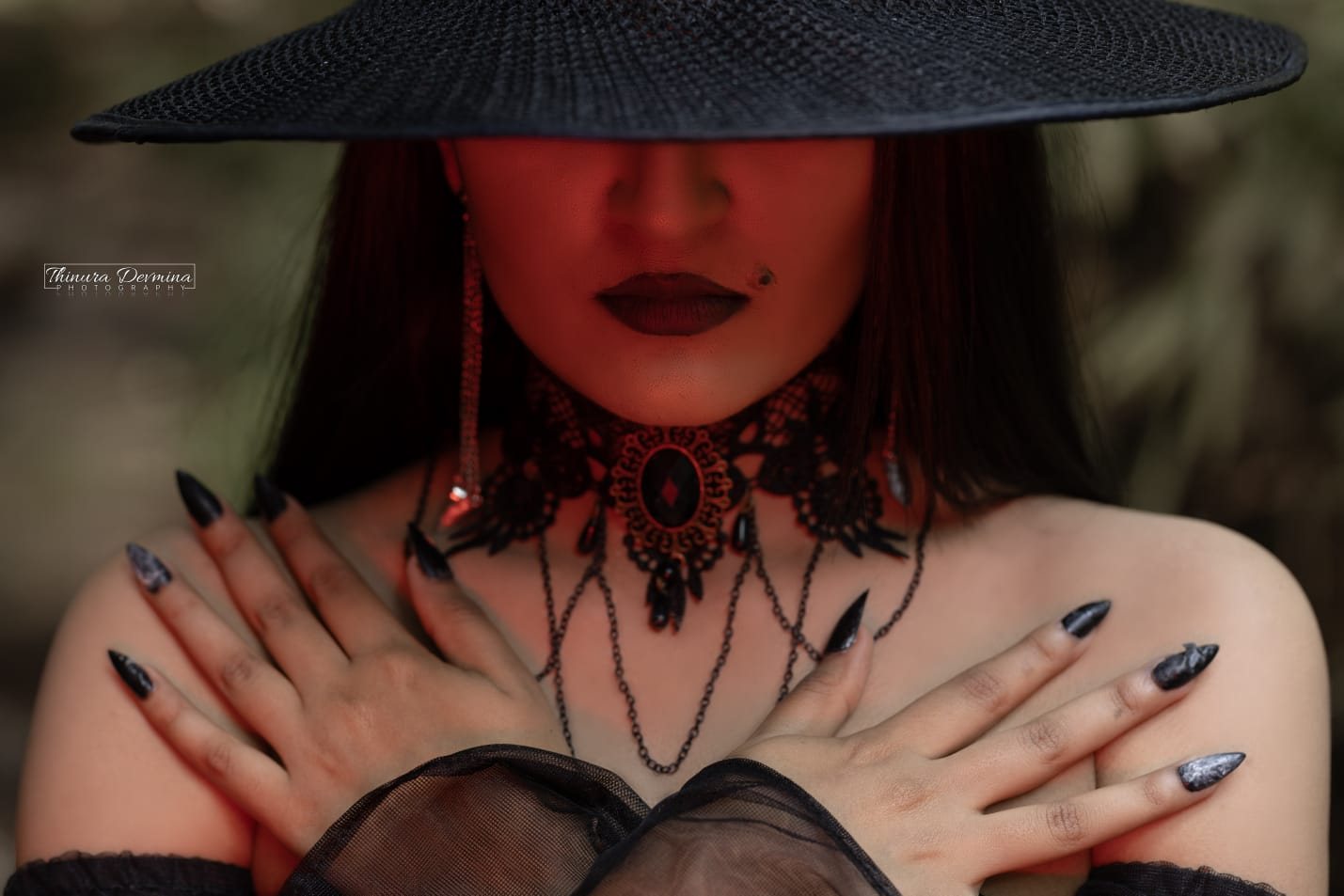 Gothic fashion portrait in a black wide-brim hat lit with crimson light