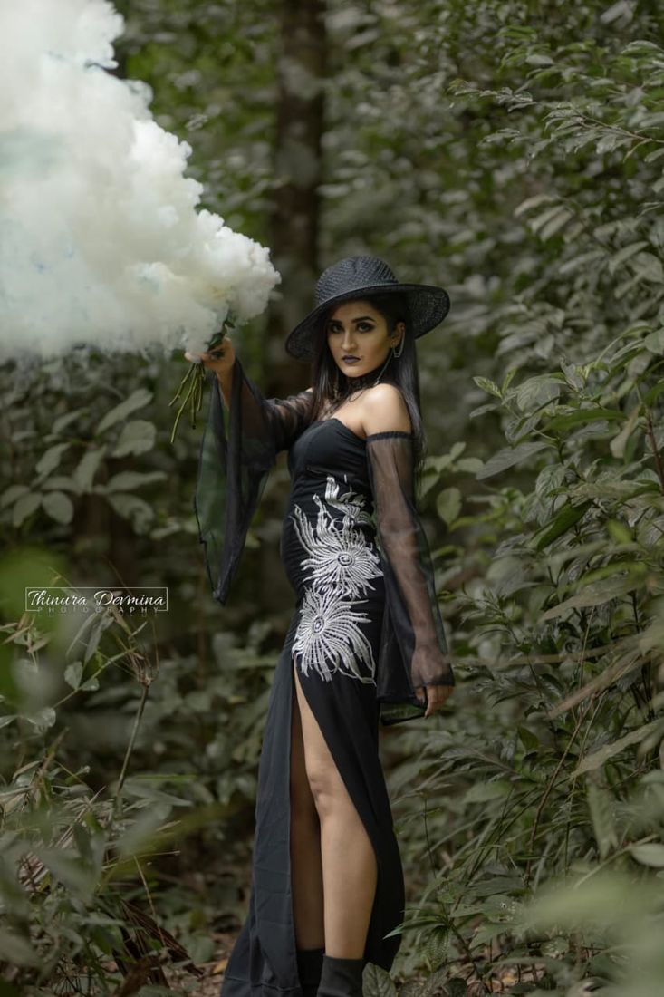 Model in a forest holding a white smoke flare